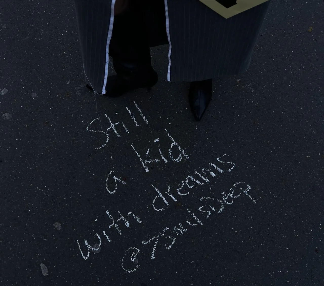 « Still a kid with dreams » écrit à la craie sur un trottoir sombre