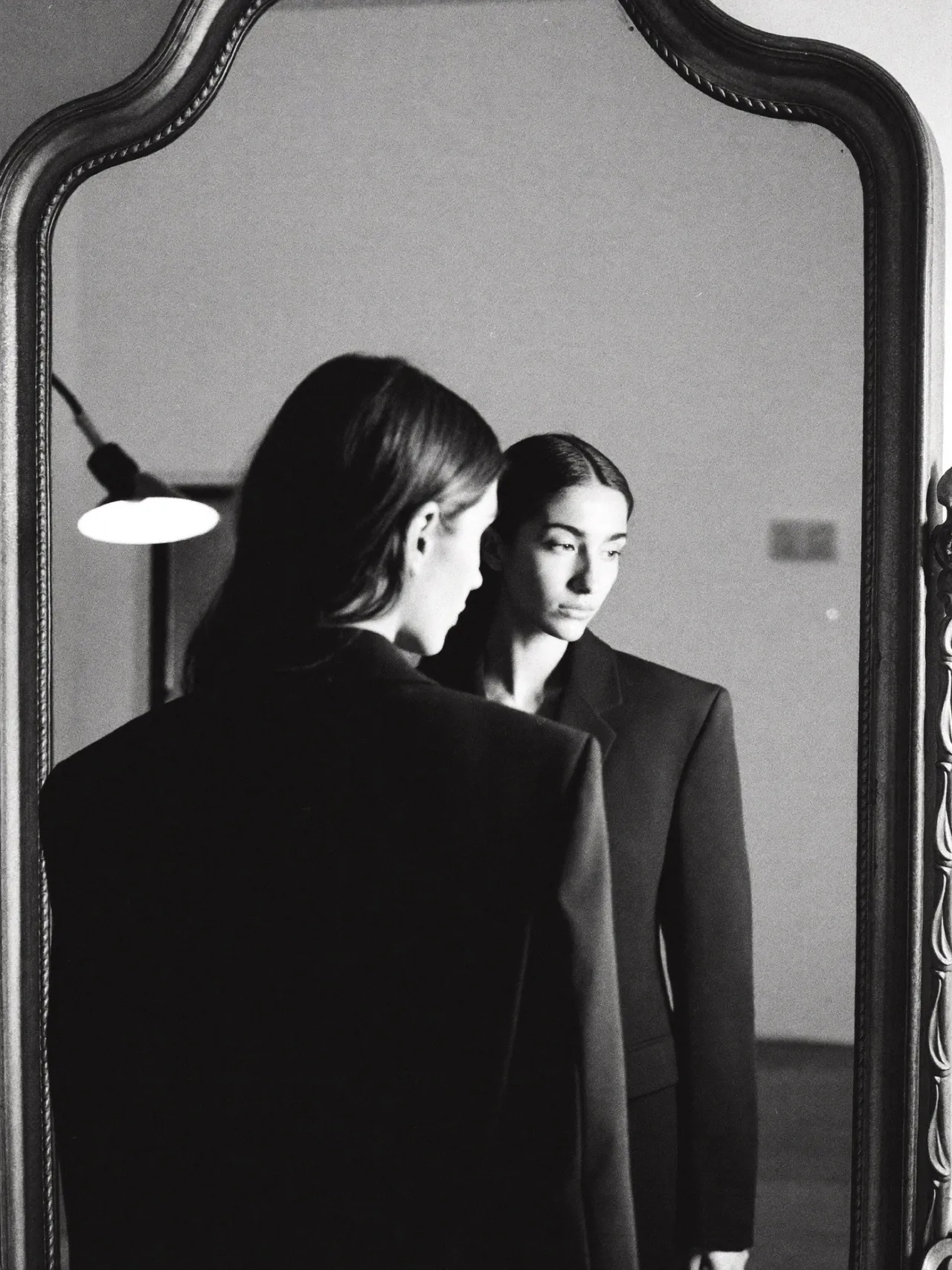 Deux femmes en costume noir reflétées dans un miroir ancien